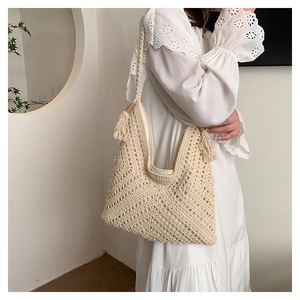 Détail du sac bandoulière tissé crème avec texture ajourée et pompons latéraux
