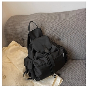 Detail view of black waterproof nylon backpack with drawstring closure and buckle on sofa