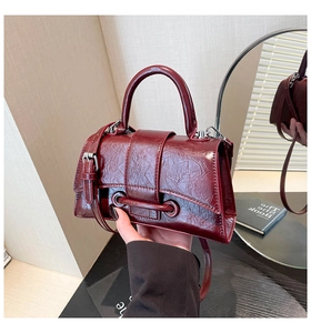 Detailed view of the burgundy hourglass bag featuring glossy oil-wax texture and strap