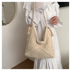 Détail du sac à bandoulière au crochet fait main avec texture géométrique et pompons latéraux