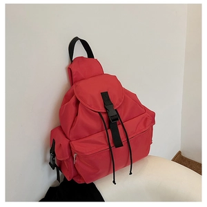 Detail view of red waterproof nylon backpack with black webbing strap and plastic buckle