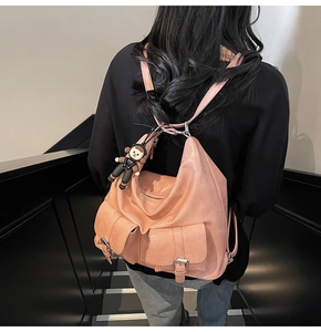 Pink faux leather backpack with double front pockets and adjustable straps shown on model