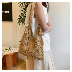 Détail du sac cabas en paille tissé à la main avec motifs au crochet et pompons