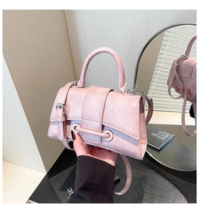Detail of light pink wrinkled texture handbag with silver metal buckle and top handle