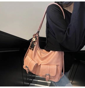 Detailed side view of a pink wax leather tote bag with dual front pockets and doll charm