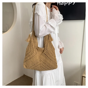 Détail d'un sac à bandoulière bohème en paille tissée avec une décoration de pompons stylée