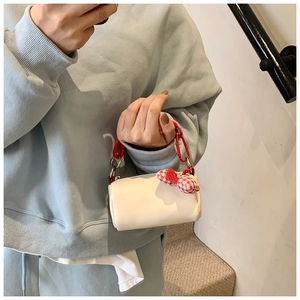 Mini borsa cilindrica bianca con manico a catena rossa e ciondolo a cuore a quadretti