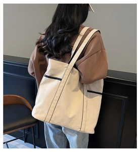 Rückansicht eines Modells mit der großen Canvas-Tragetasche in Creme mit schwarzen Riemen