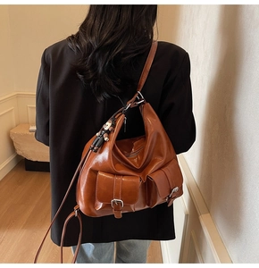 Detail showing two front flap pockets with silver hardware on brown wax leather tote