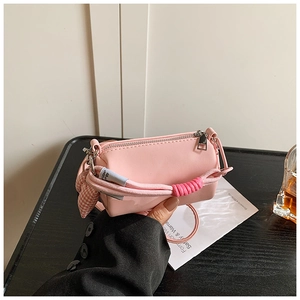 Dettaglio della borsa a cilindro rosa in PU con manico intrecciato e ciondolo a quadri