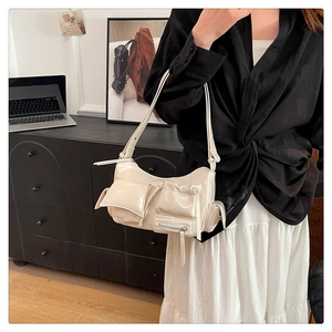 Close-up of cream faux leather shoulder bag with multi-pocket design and glossy finish