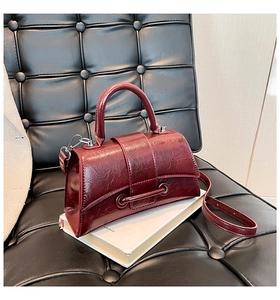 Close-up of deep red vintage leather handbag with textured finish on a white book