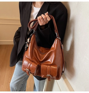 Detail view of retro brown wax leather tote bag with dual front pockets and bear charm