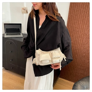 Detail view of cream white multi-pocket biker crossbody bag in glossy faux leather finish
