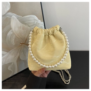 Detail der gelben Satin-Beuteltasche mit großem Kunstperlengriff und goldener Kette