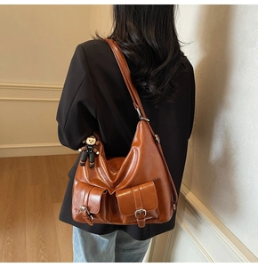 Detail of vintage caramel tote bag featuring dual front pockets and adjustable straps