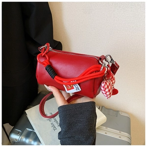 Dettaglio borsa a cilindro rossa con tracolla in corda intrecciata e ciondoli a cuore