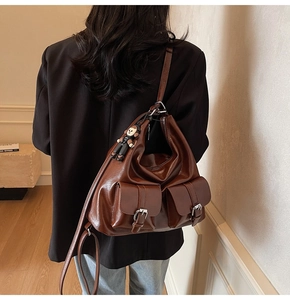 Detail of vintage oil wax leather tote bag with functional front flap pockets and doll charm