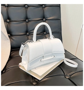 Detailed macro view of white textured faux leather bag with curved base and silver hardware