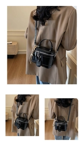 Detail of black box vanity bag featuring silver zippers and a textured tassel charm
