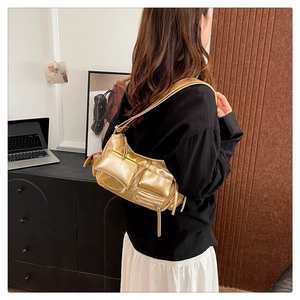 Detailed close-up of metallic gold hobo bag with multiple pockets and trendy tassels
