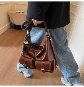 Detail of dark brown leather hobo bag with vintage buckle pockets and a cute charm