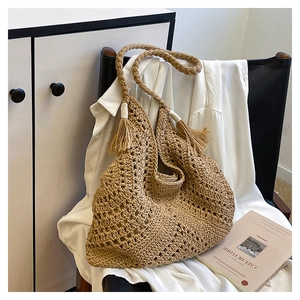Détail du sac bandoulière en paille tressée avec pompon et bandoulière en maille texturée