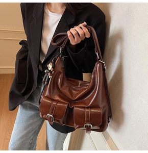 Detail view of brown oil wax leather tote bag with functional pockets and bear keychain