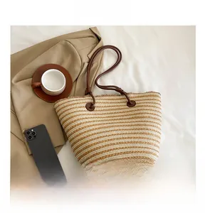 Détail de la texture tissée et des anses en similicuir marron sur un grand sac cabas