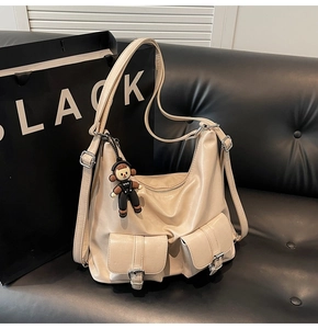 Detail view of beige oil wax leather tote with multi-pockets and cute pendant