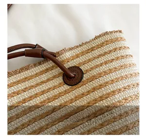 Détail de la texture tressée en paille et des coutures de la poignée en cuir du sac cabas