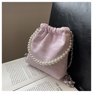 Detail einer hellrosa Beuteltasche mit Perlengriff und Marmorstruktur auf Leder