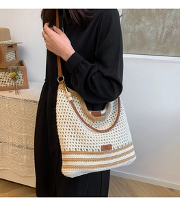 Close-up of minimalist woven shoulder bag featuring brown leather strap and contrast stripes
