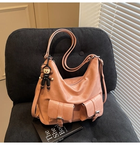 Detailed close-up of pink hobo bag with twin buckle pockets and a black doll pendant
