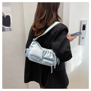 Detail of light blue PU leather multi-pocket shoulder bag styled on a black blazer