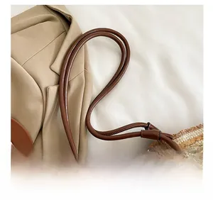 Détail de la fine bandoulière en cuir marron et texture paille tressée avec franges