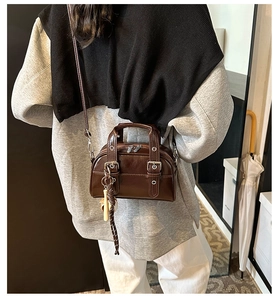 Detailed view of dark brown Boston bag with polished synthetic leather and rivet accents