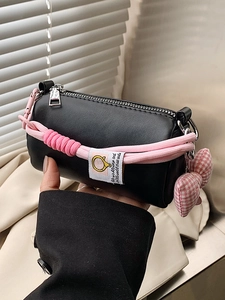 Borsa a cilindro nera minimalista con manico a corda rosa e ciondolo a fiocco