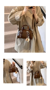Close-up of small dark brown oil-wax leather handbag with silver buckle and ribbon charm