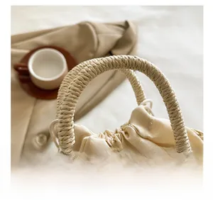 Close-up of woven handle and beige cotton drawstring lining of the minimalist straw beach bag
