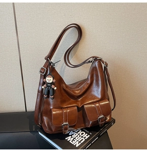 Detail of vintage brown oil wax leather tote bag with functional pockets and doll charm