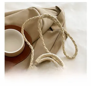 Detail of the woven shoulder strap on the beige straw bag with a textured finish