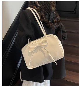 Close-up of cream bow-knot shoulder bag with dual straps and smooth PU leather texture