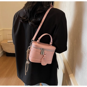Detail of pink patent leather box bag with metal double zippers and tassel charm detail