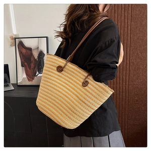 Détail du sac cabas en paille tressée avec motifs rayés et bandoulières en cuir souple