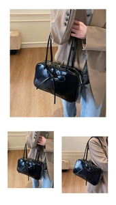 Macro view of a black glossy patent leather Boston bag featuring a large decorative bow