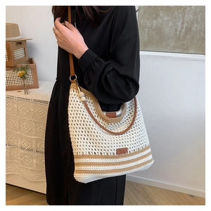 Detail of hand-woven off-white shoulder bag featuring brown stripes and leather strap accents