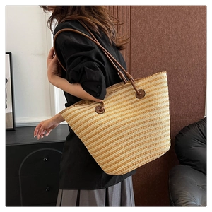 Détail du sac cabas en paille tressée avec anses en cuir marron et texture tissée