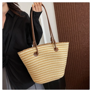Détail du sac cabas tissé beige avec poignées en cuir marron et bords à franges
