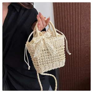 Detail of hand-woven beige beach bag featuring a delicate white lace bow and drawstring